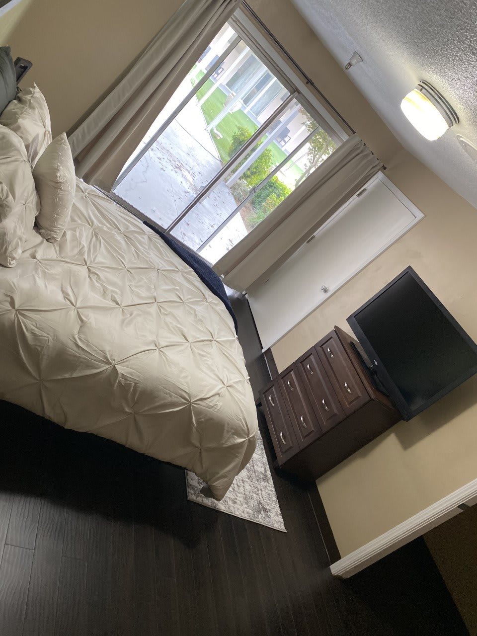 A cozy bedroom with a neatly made bed, dresser, and wall-mounted television.