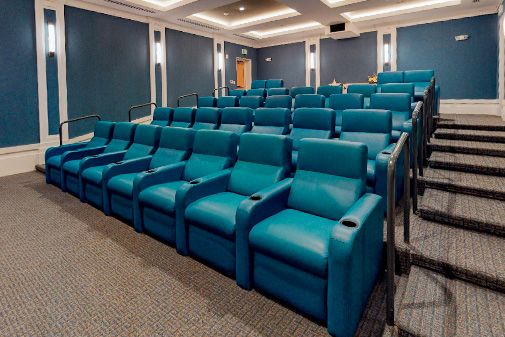 An empty theater with rows of comfortable blue seats.
