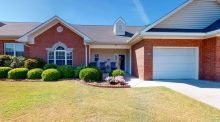 A brick single-story house with a front lawn and attached garage.