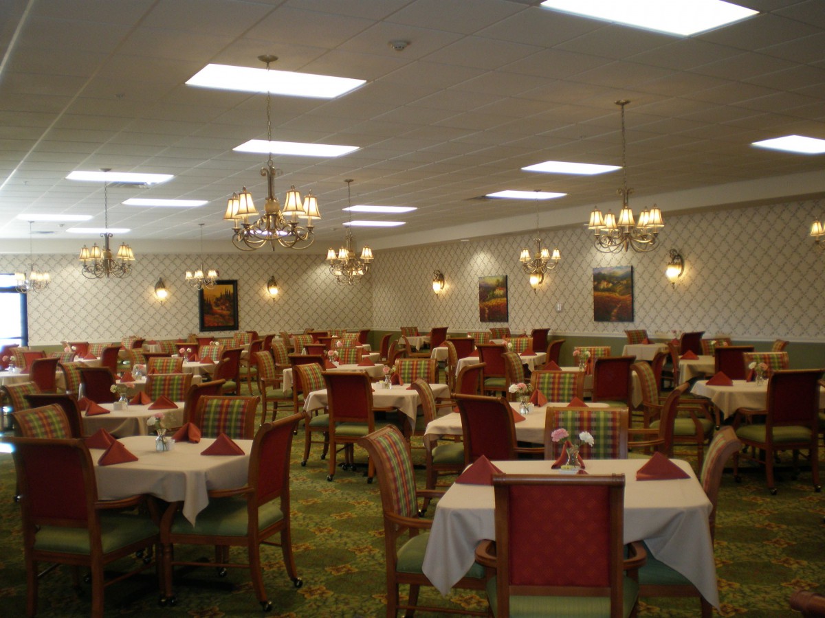 An elegantly set dining room with multiple tables and chandeliers overhead.