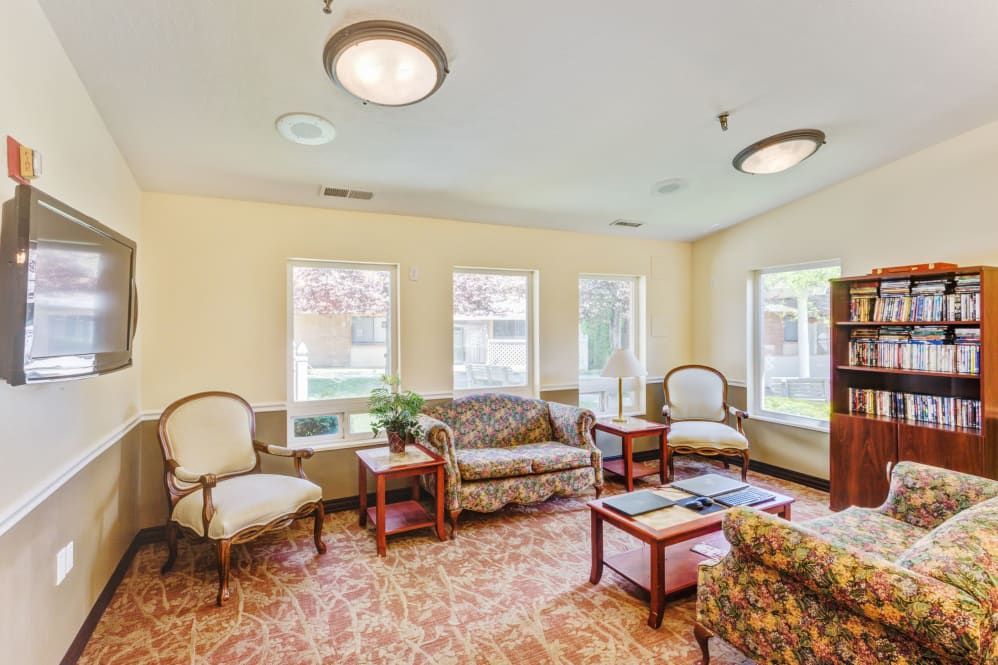A cozy living room with sofas and chairs arranged around a central table under soft lighting.