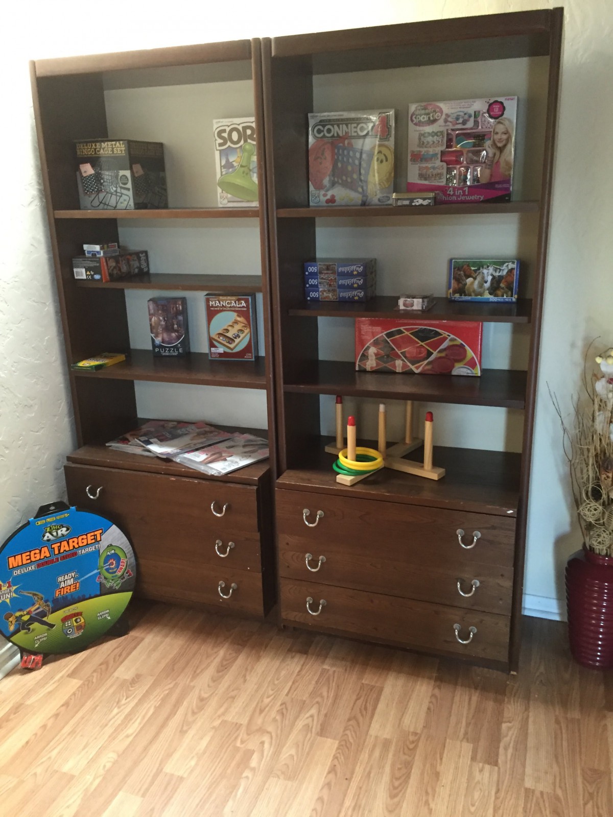 A pair of wooden bookshelves filled with toys and games, offering a tidy storage solution in the corner of a room.