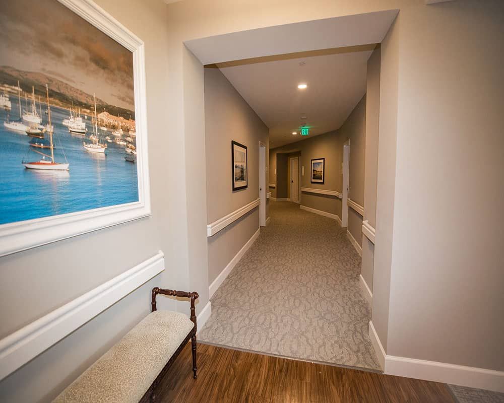 A modern hallway with artwork and seating, featuring carpeted flooring and ceiling lights.