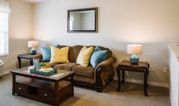 Cozy living room with a brown sofa, colorful pillows, and ambient lighting.