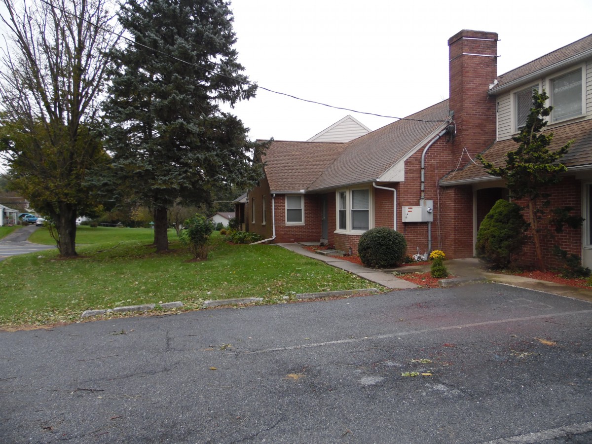 A suburban brick house with a driveway and a well-maintained yard.