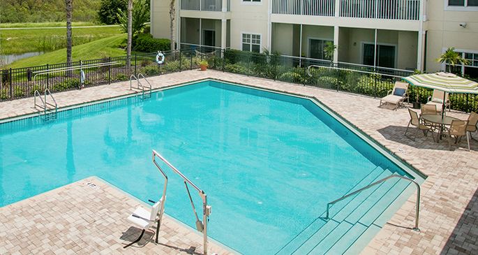 An outdoor swimming pool in a residential area with clear blue water.
