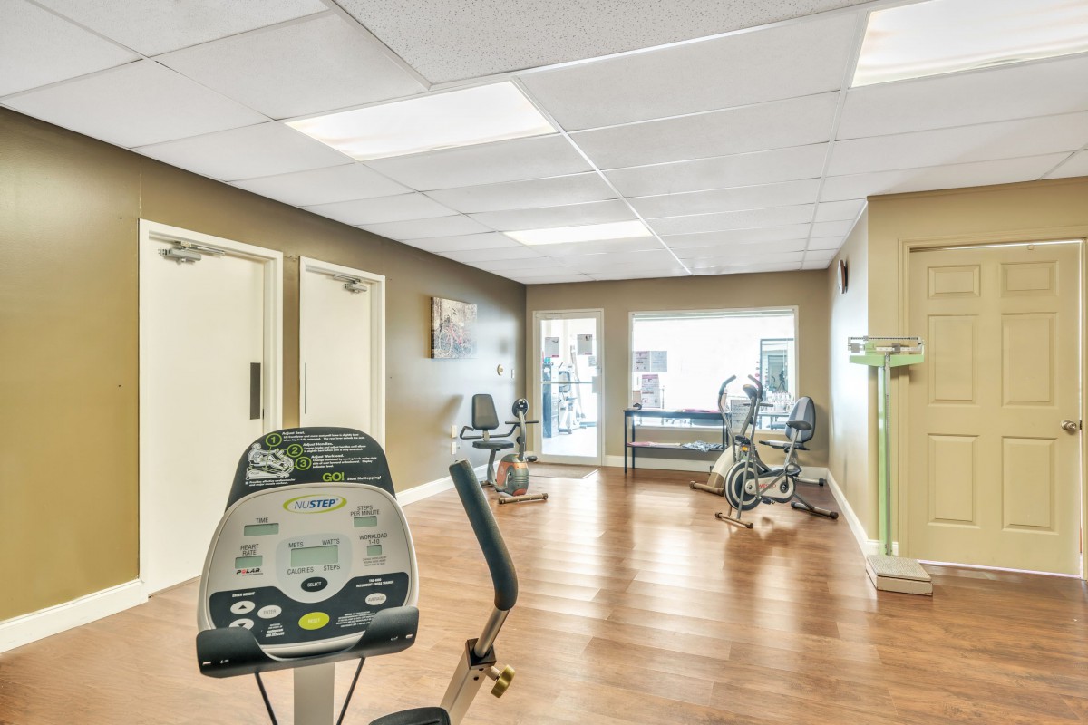 A well-lit gym featuring various exercise equipment in a spacious interior.