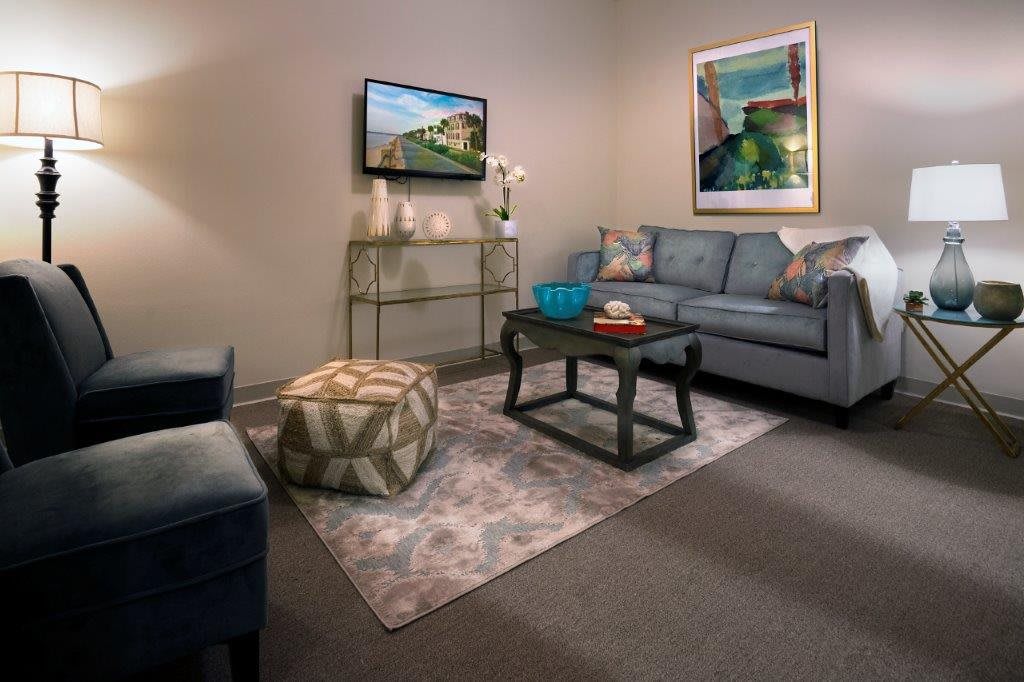 A cozy living room with a comfortable sofa, decorative artwork, and a television mounted on the wall.
