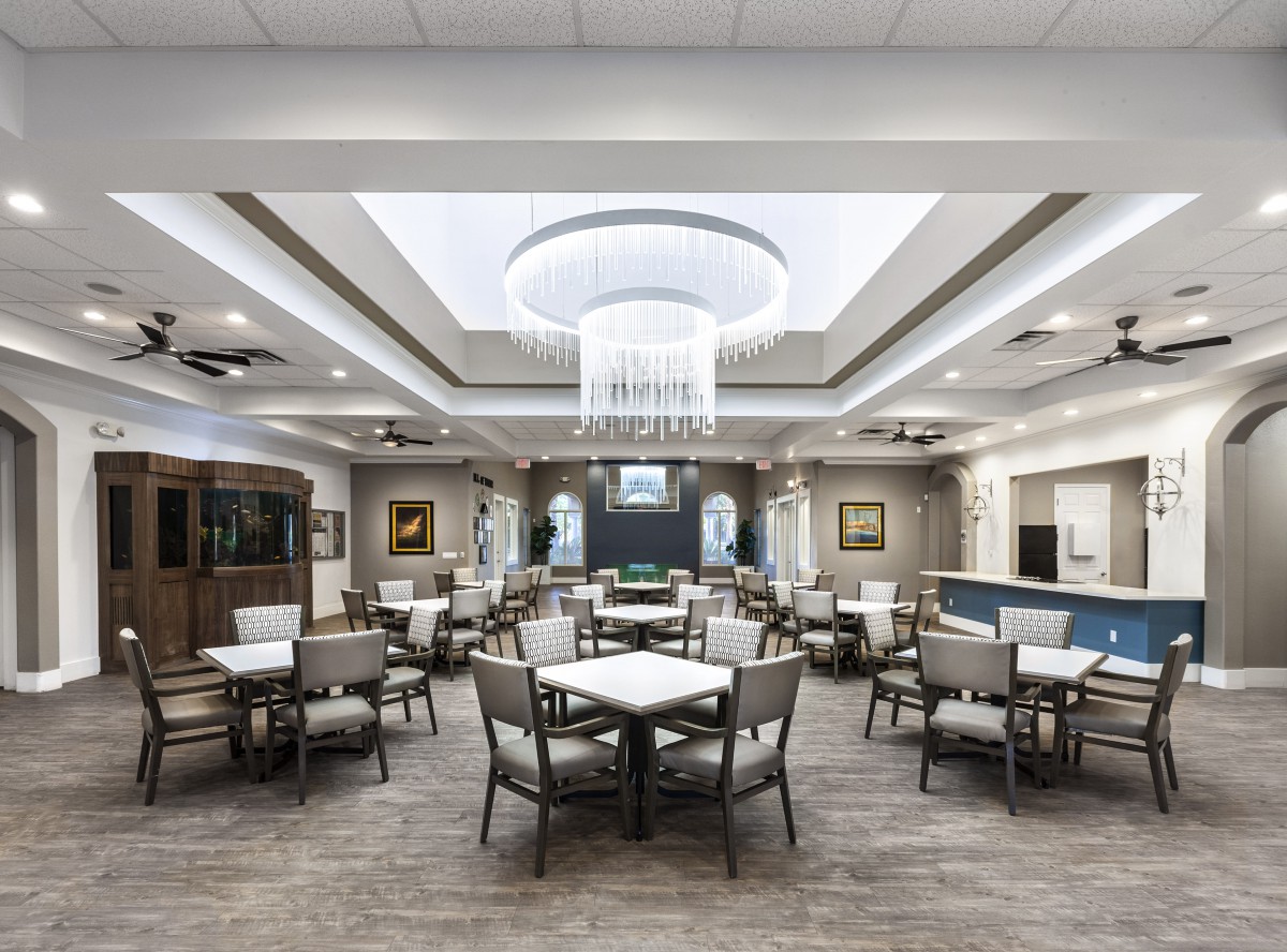 A modern dining room with neatly arranged tables and chairs under elegant ceiling lights.