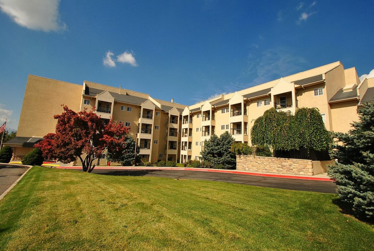 A sunny day view of a residential apartment building with well-maintained landscaping.