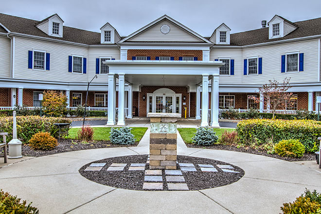 A symmetrical two-story building with columns at the entrance and well-maintained landscaping.
