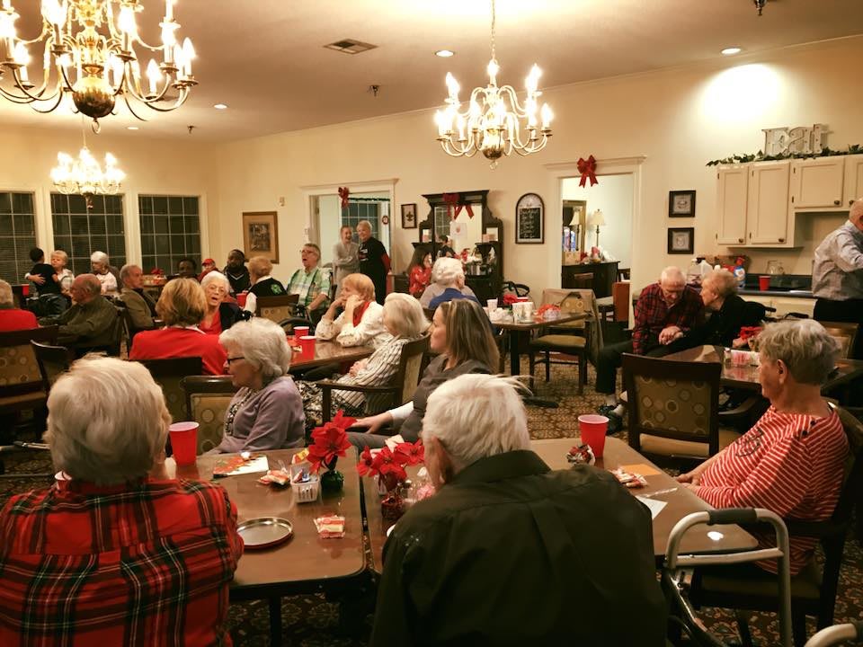 A group of seniors gathered indoors for a community event, enjoying conversation and companionship.