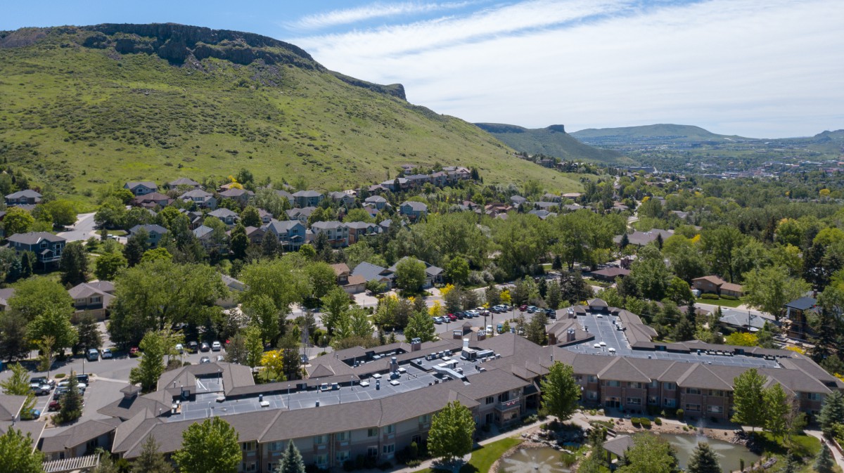 Aerial view of a town nestled among green hills, showcasing buildings and lush greenery.