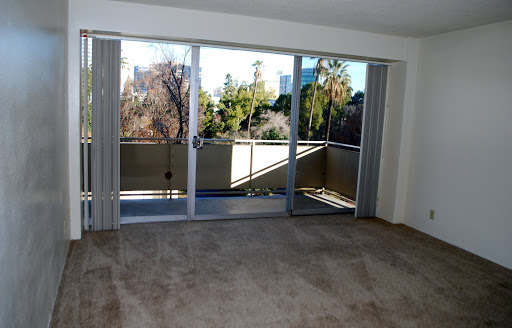 A spacious living room featuring sliding doors that open to a balcony, with plenty of natural light filtering in.