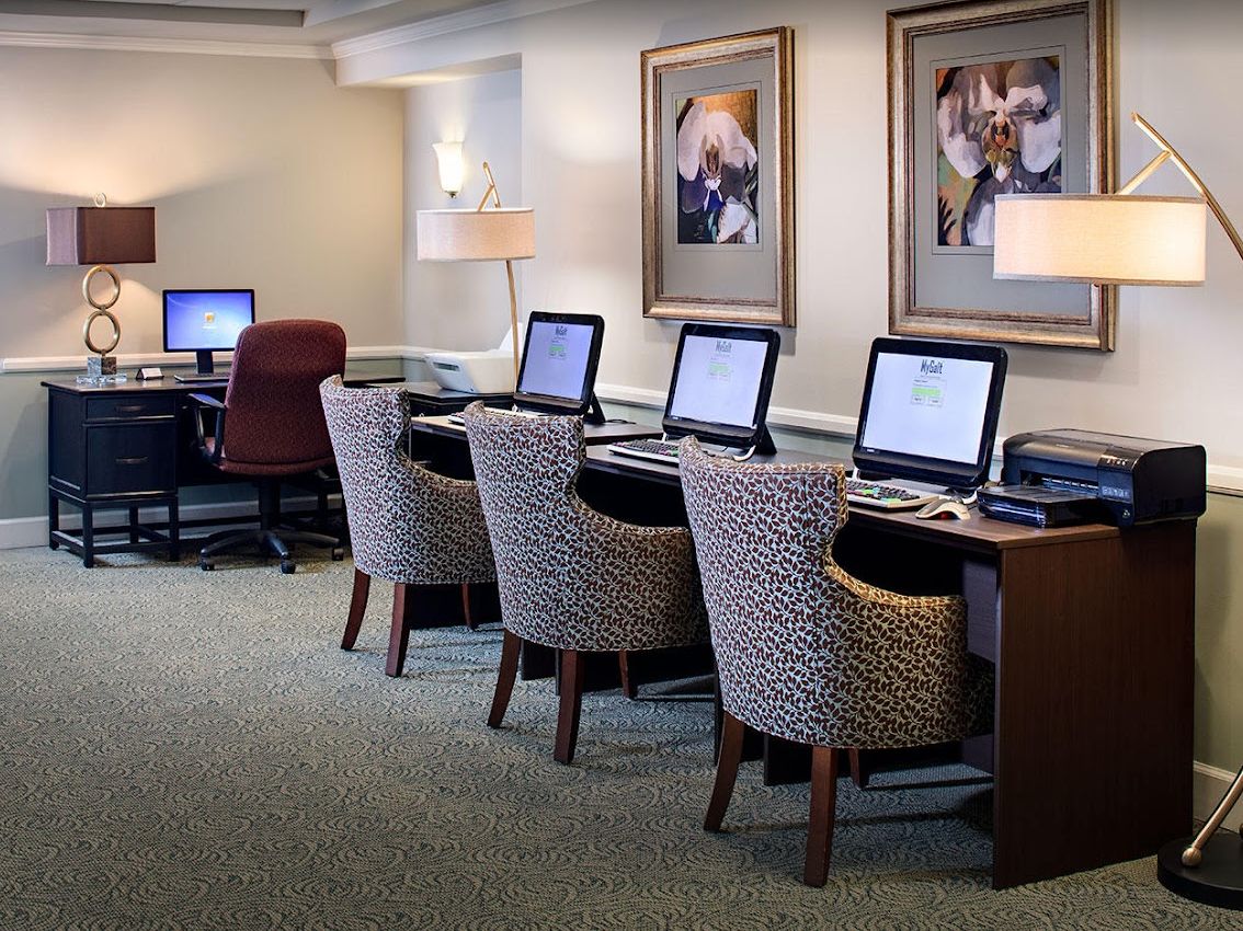A modern business center with computers and comfortable chairs.