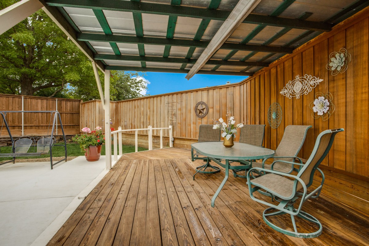 A cozy outdoor patio with a wooden deck and seating area under a cover.