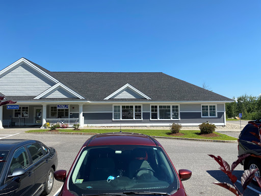 A modern building with a well-maintained facade, surrounded by cars under a clear blue sky.