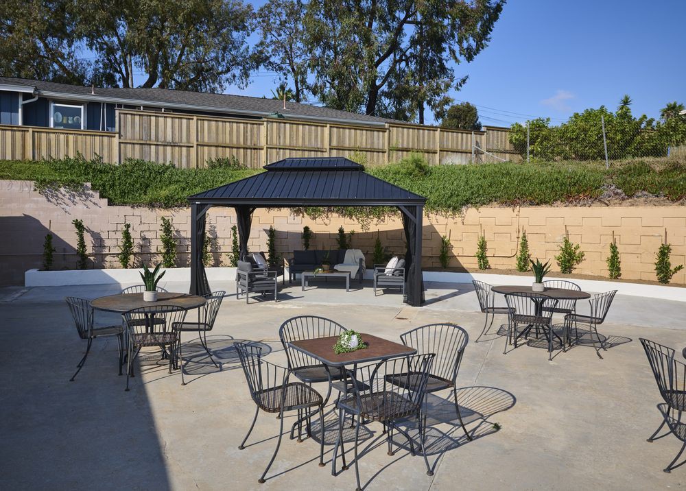 A well-furnished outdoor patio featuring a gazebo and several tables and chairs.