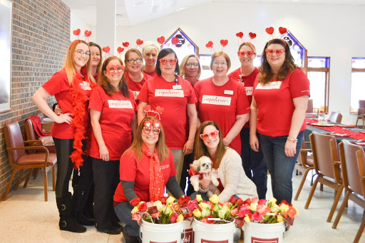 A cheerful team dressed in red, celebrating together with flowers and heart decorations.