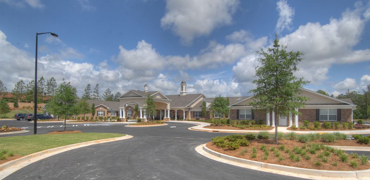 A scenic view of a residential building with a spacious driveway and a cloudy sky.