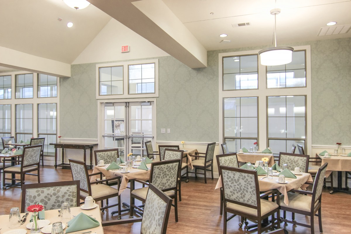 A well-lit dining room with neatly arranged tables and chairs.