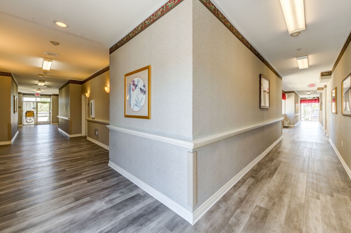 A modern hallway with artwork, wooden flooring, and soft lighting.