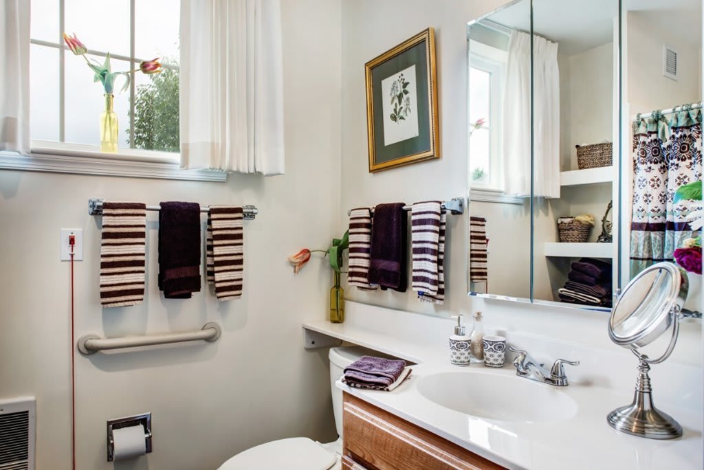 A cozy bathroom with striped towels, a large mirror, and decorative elements.