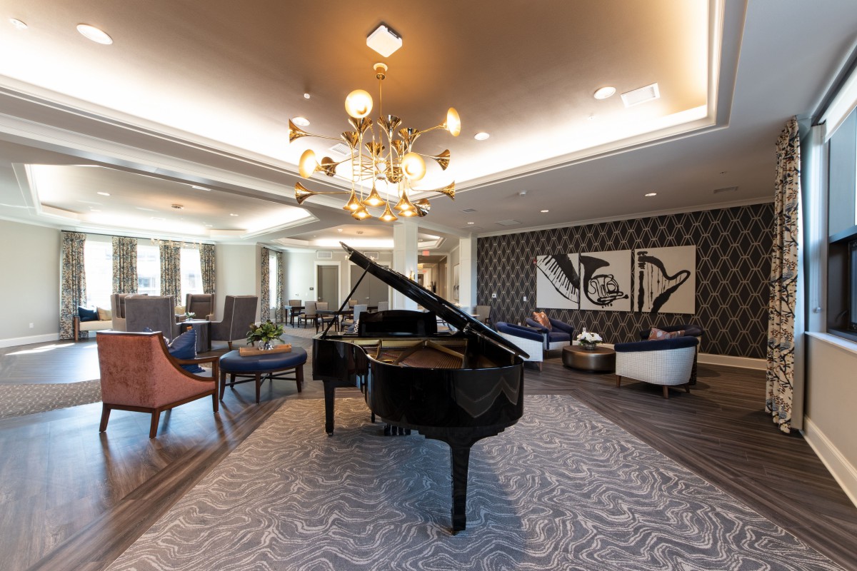 A modern lounge featuring a grand piano, elegant furniture, and stylish lighting.