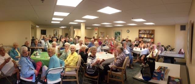 A group of seniors gathered indoors for a community meeting.