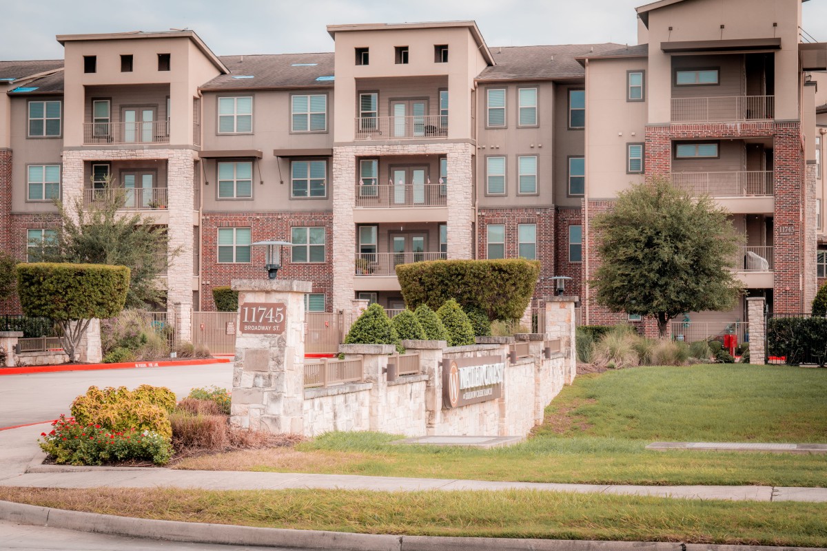 A view of a modern apartment building with landscaped surroundings.