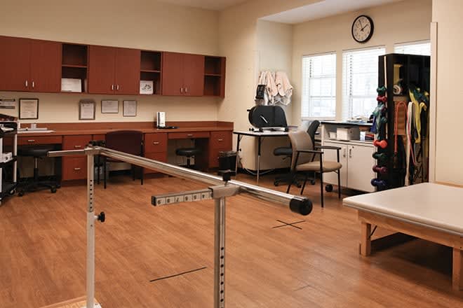 A rehabilitation room equipped with parallel bars and various exercise tools, designed for physical therapy.
