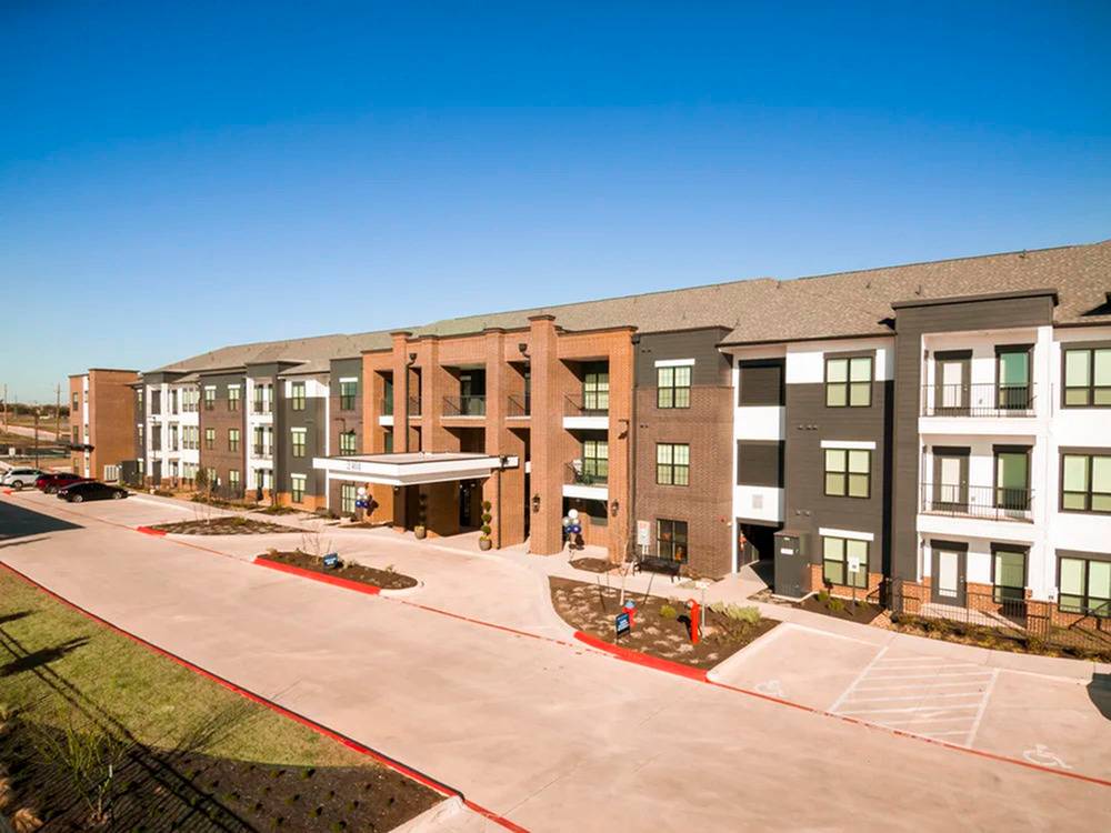 A modern residential apartment complex under a clear blue sky.