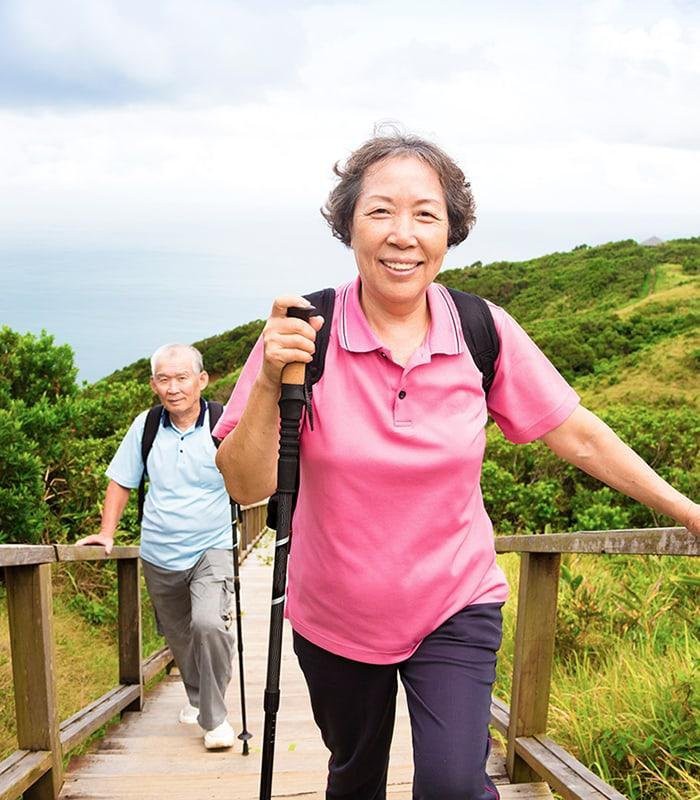 An elderly couple enjoys a hike through scenic nature trails.