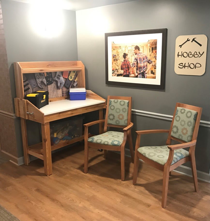 A cozy corner workshop setup with a wooden desk and tools, accompanied by a pair of upholstered chairs.