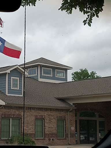 A Texas flag flies in front of a building under a cloudy sky.