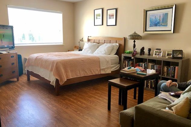 A cozy bedroom with a large bed, wooden flooring, and wall decorations.