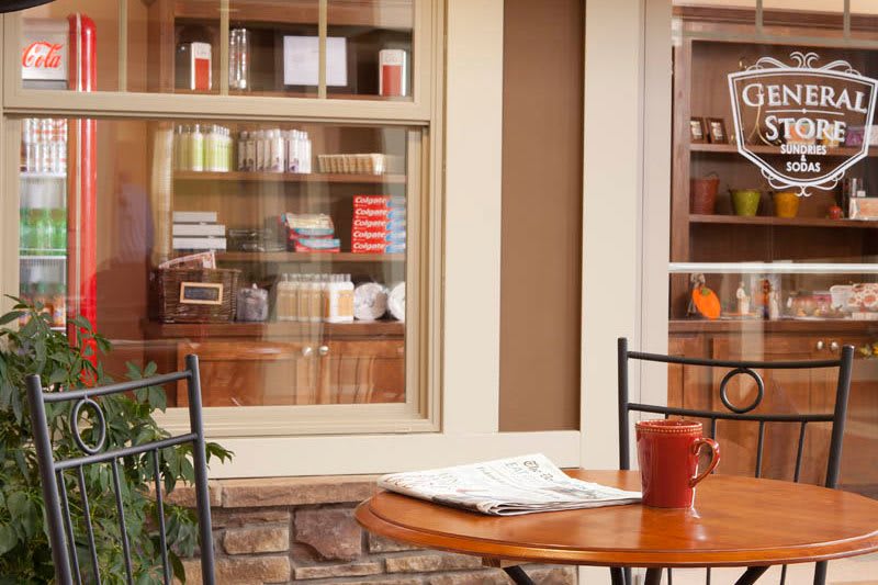A cozy outdoor patio with a table, coffee cup, and a view of a bookshelf through the window.