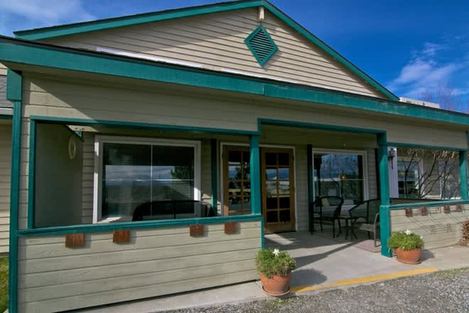 A small building with a porch and large windows under a clear blue sky.