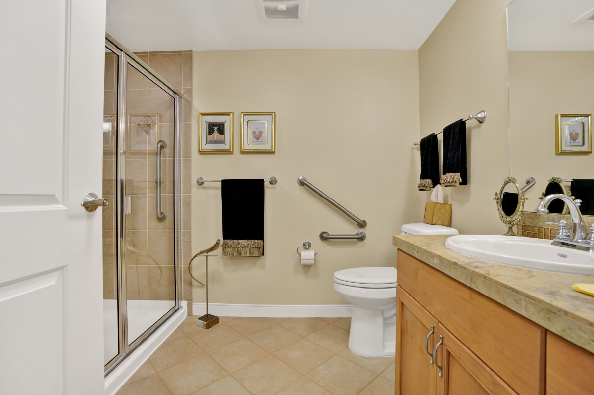 A well-organized bathroom with a glass-enclosed shower, toilet, and double sinks.