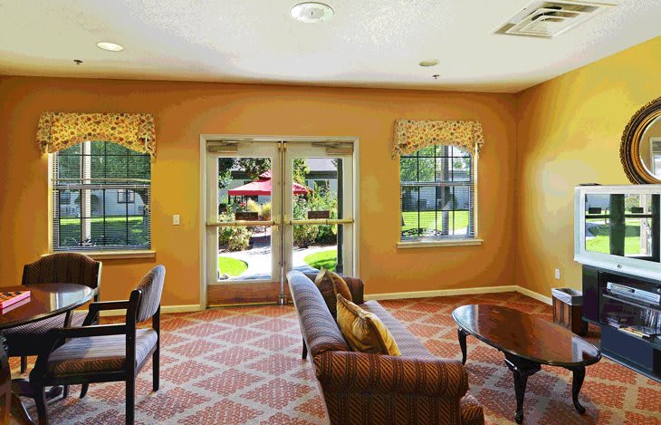 A warmly lit lobby with seating area and large windows overlooking an outdoor space.
