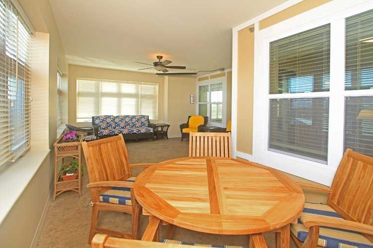 A bright indoor living space featuring wooden furniture and a ceiling fan.