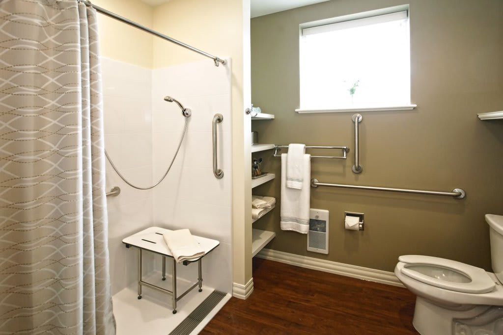 An accessible bathroom with a walk-in shower, grab bars, and a shower bench.
