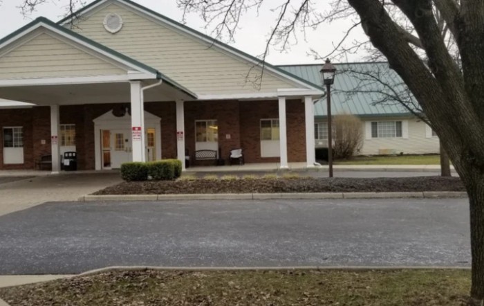 A brick building with white columns at the entrance, viewed from across a road.