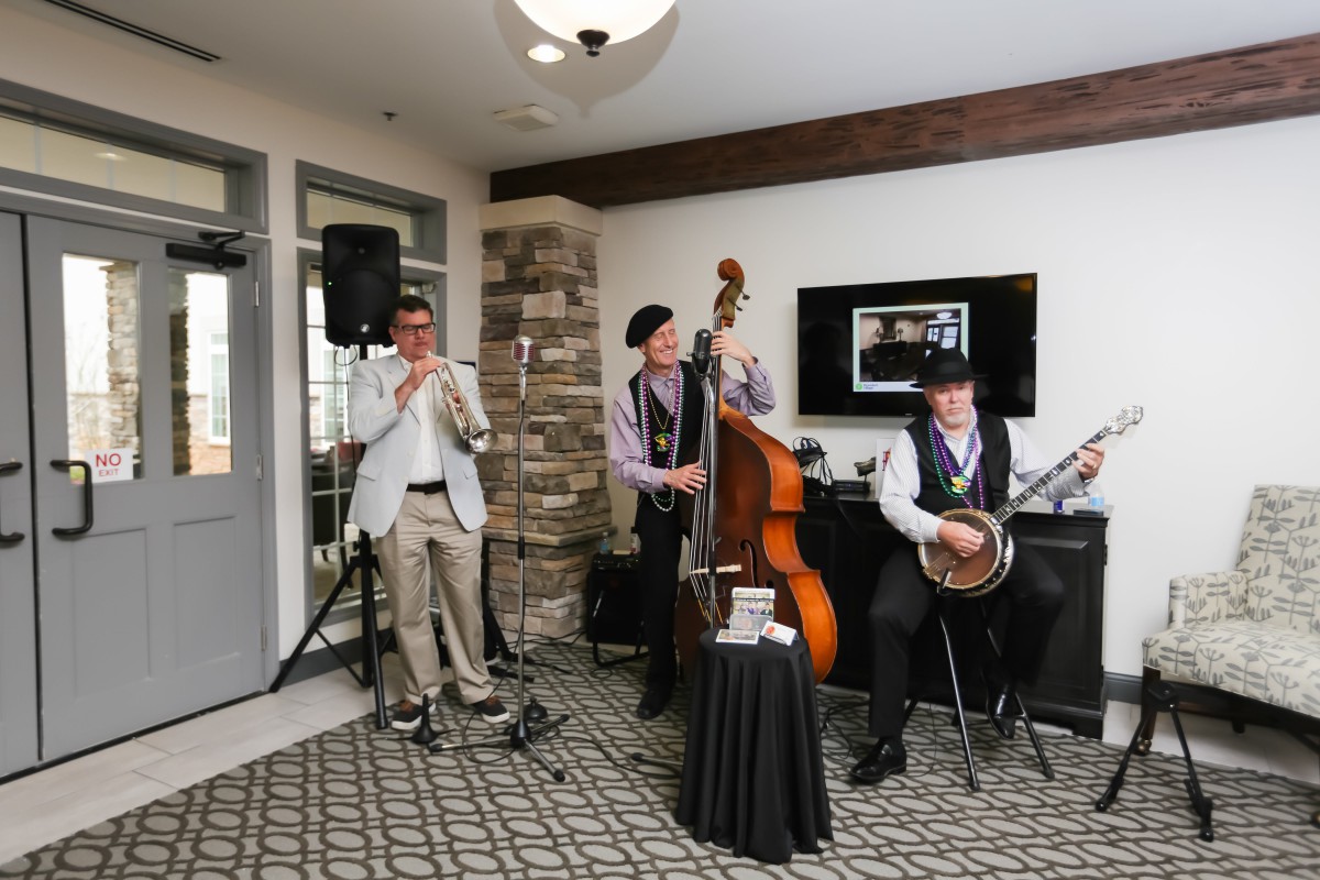 A jazz band performing indoors with a trumpet, double bass, and banjo.