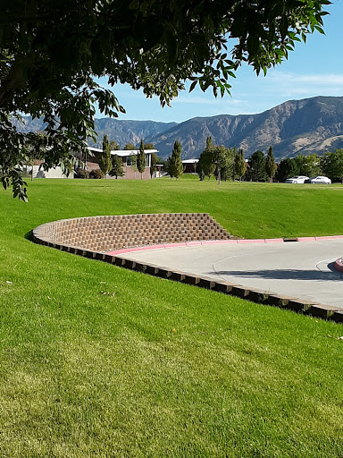 A scenic view of a park featuring a curved brick edge and green grass with mountains in the background.