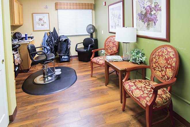 A cozy waiting area in a hair salon featuring patterned chairs and wooden floors.