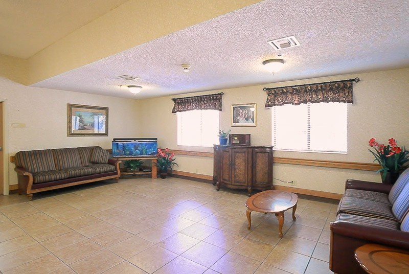 A spacious living room with a sofa, aquarium, and coffee table beneath large windows.