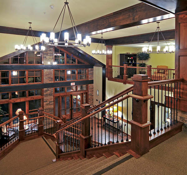Spacious interior with wooden staircase and chandeliers.