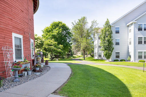 A serene pathway winding through a residential area, surrounded by lush greenery and well-maintained buildings.