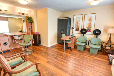 A cozy hair salon interior featuring wooden floors, comfortable chairs, and modern equipment.